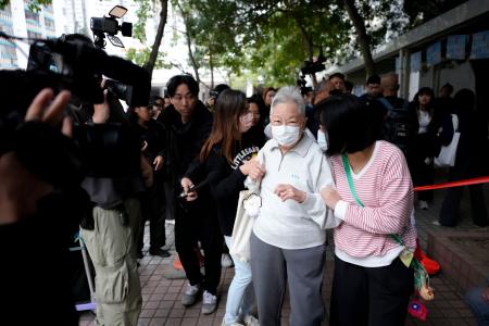 　生活必需品や貴重品を取るために火災があった高層住宅群に向かうお年寄り（手前左）＝３日、香港（共同）