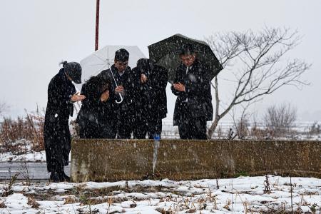 　能登半島地震で犠牲になった親族の自宅跡で手を合わせる人たち＝１日午後１時５８分、石川県珠洲市宝立町