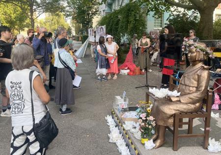 　韓国系市民団体「コリア協議会」などが開いた集会で、少女像の周囲に立つ人々＝１４日、ベルリン（共同）