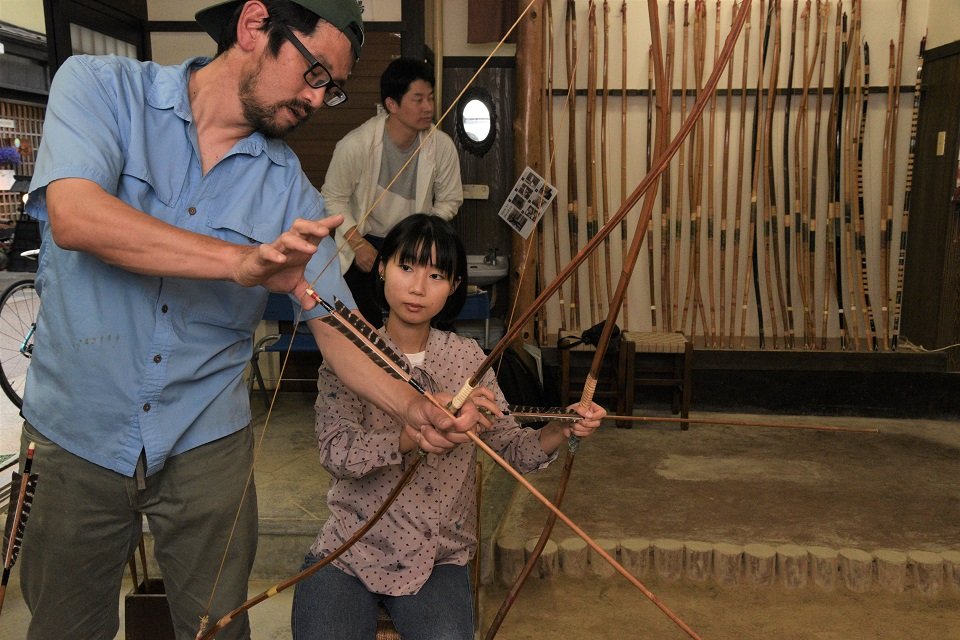 来店客に弓矢の扱い方を説明するのは、店を切り盛りする黒岩直己さん（左）＝高山市朝日町、半弓道場