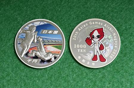 　第２０回アジア競技大会を記念した千円銀貨。右は公式マスコットの「ホノホン」を描いた裏面