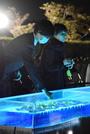 　中華航空機墜落事故から３１年となり、水槽に花を供える参列者＝２６日夜、愛知県春日井市