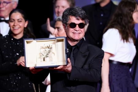 　第７８回カンヌ国際映画祭の授賞式で、最高賞パルムドールのトロフィーを掲げ、笑顔を見せるジャファル・パナヒ監督＝２４日、フランス・カンヌ（ゲッティ＝共同）