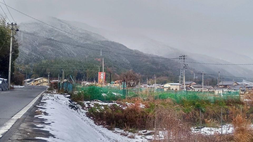 路肩に雪が積もり、山は雪化粧した＝１８日午前９時３０分、揖斐郡池田町片山