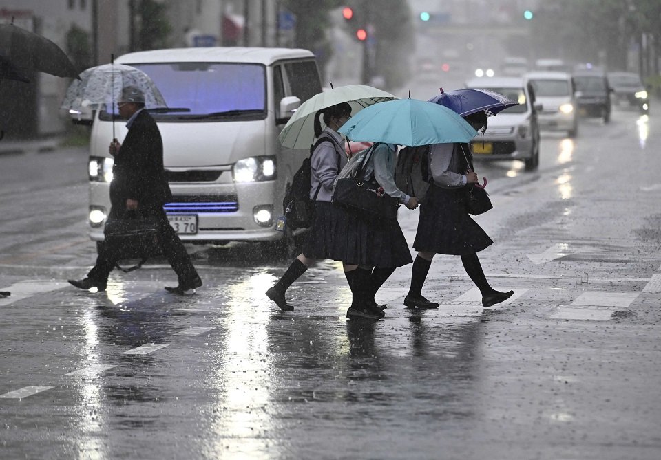 大雨の中、横断歩道を渡る人たち＝２日午後０時３分、岐阜市神田町
