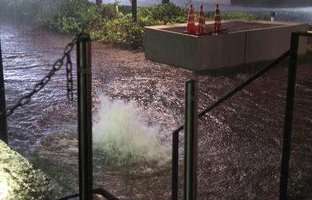 　大雨の影響で水が噴き出すマンホール＝１３日午後７時２分、千葉市中央区