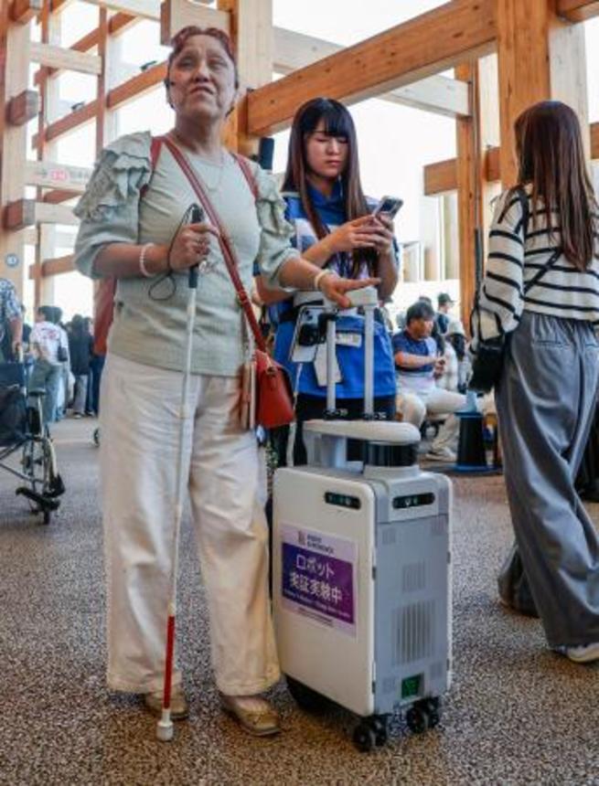 　大阪・関西万博会場で「ＡＩスーツケース」の実証実験に参加した久保田真智子さん（左）＝１０月、大阪市此花区の夢洲