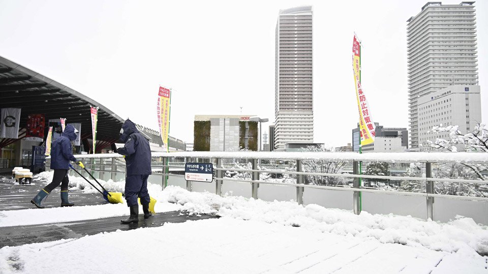 歩行者デッキに積もった雪を除く関係者＝５日午前９時７分、岐阜市橋本町、ＪＲ岐阜駅北口