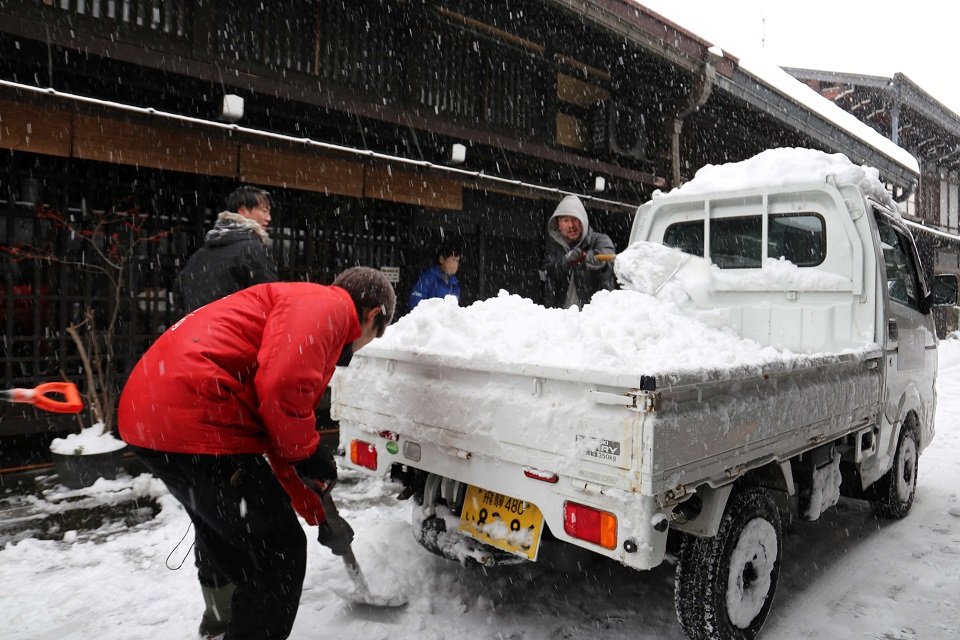 よけた雪を軽トラックの荷台に積む市民ら＝２４日午前１０時１７分、高山市上三之町