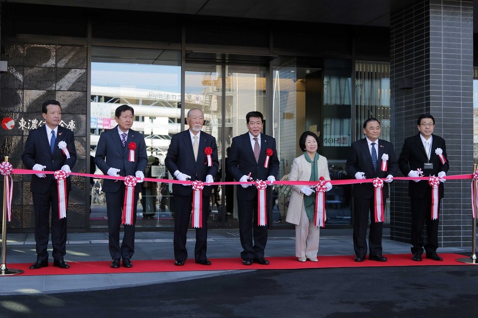東濃信用金庫新本店ビルのグランドオープンをテープカットで祝う関係者＝多治見市本町