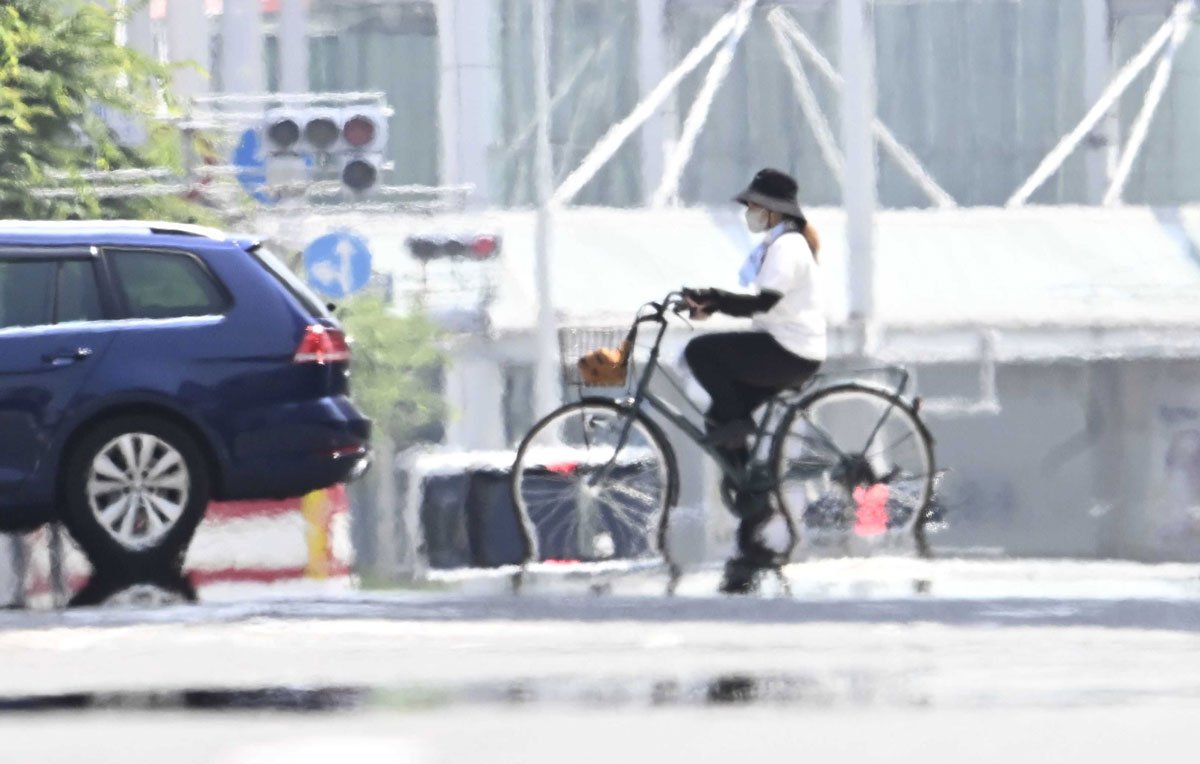猛暑で逃げ水現象の現れた道路を渡る自転車＝２１日午後１時４０分、岐阜市神田町（撮影・堀尚人）
