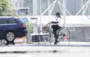 猛暑で逃げ水現象の現れた道路を渡る自転車＝２１日午後１時４０分、岐阜市神田町（撮影・堀尚人）
