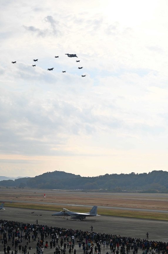 Ｃ１輸送機を先頭にした三角形のデルタ隊形で飛行する異機種大編隊＝１３日午前８時４２分、各務原市、航空自衛隊岐阜基地