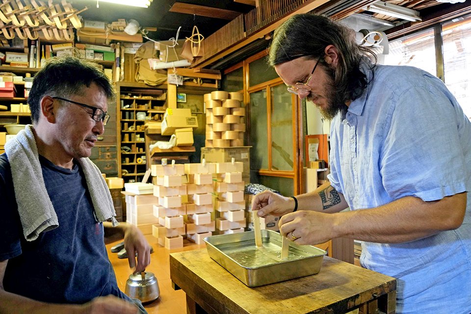伝統工芸士の西田恵一さん（左）から曲げ物の技術指導を受けるブレンダン・ガフニーさん＝高山市内