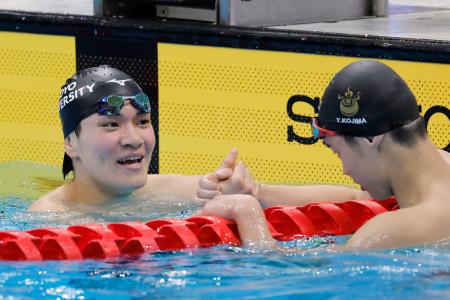 　男子４００メートル個人メドレー決勝のレース後、２位となった小島夢貴（手前）と健闘をたたえ合う優勝した松下知之＝東京アクアティクスセンター