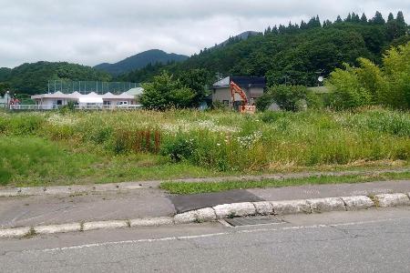 　男性が倒れていた草地。左奥はグループホーム＝１２日午前、北海道福島町