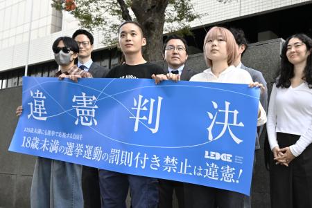 　１８歳未満の選挙運動を禁止する公選法の規定を巡る訴訟の東京地裁判決を受け「違憲判決」と記した横断幕を手にする原告ら＝２５日午後、東京地裁前