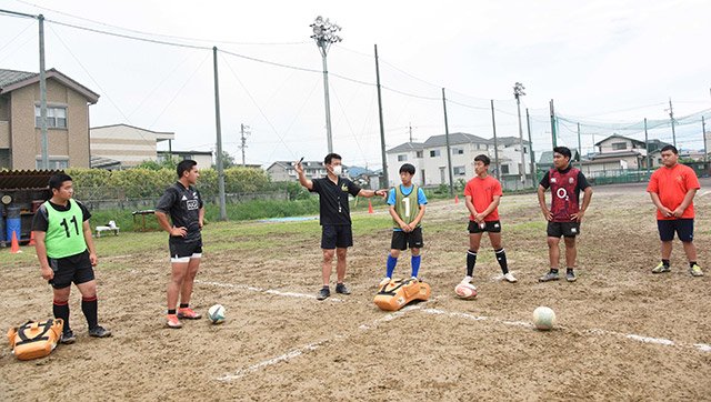 水間良武氏（左から３人目）から指導を受ける可児工の部員たち＝同校グラウンド