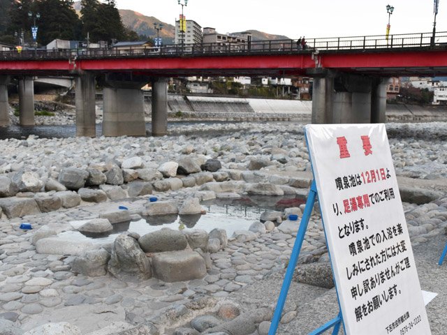 １２月から足湯専用となる噴泉池。予告の看板が設置された＝１８日午後、下呂市幸田、飛騨川河川敷