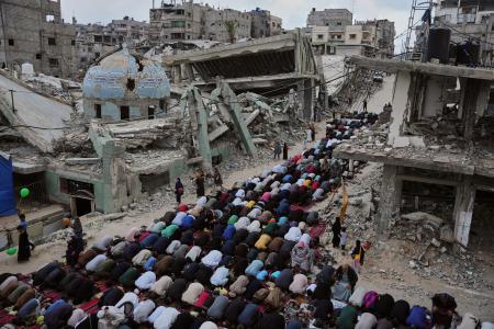 　イスラエルの攻撃で破壊されたモスクのそばで祈りをささげる人々＝２７日、パレスチナ自治区ガザ南部ハンユニス（ＡＰ＝共同）