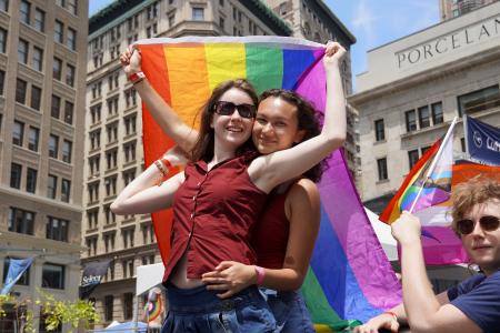 　２９日、米ニューヨークでの性的少数者のパレードで、虹色の旗を持ち抱き合う参加者（共同）