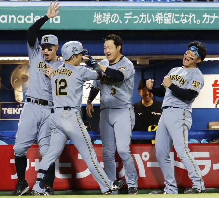 　９回、決勝本塁打を放った坂本（手前）を迎える阪神ナイン＝神宮