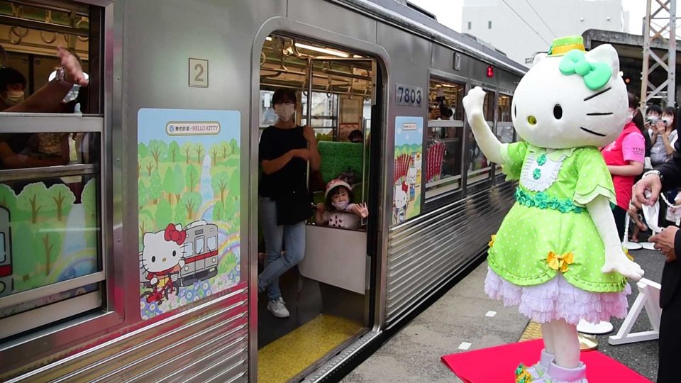 出発式に駆け付け、「ハローキティ」の装飾が施された列車の乗客を見送る「キティちゃん」＝大垣市高屋町、養老鉄道大垣駅