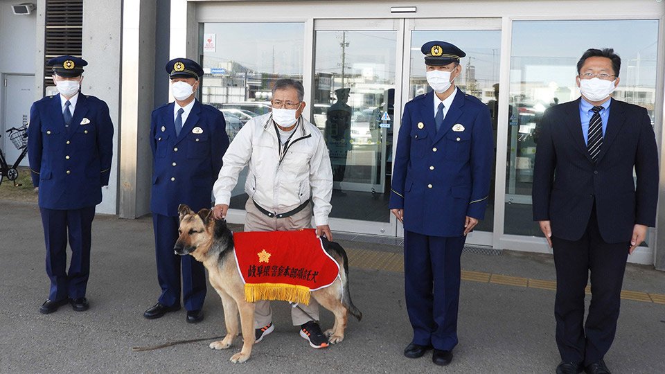 嘱託警察犬として委嘱を受けたゴーと小木曽忍さん（中央）＝岐阜南署