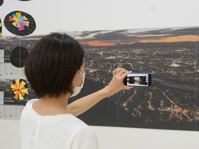 スマートフォンをパネルにかざすと、一昨年の全国花火大会の映像が楽しめる企画展＝本巣市三橋、モレラ岐阜内の「岐阜新聞メディアばこ」