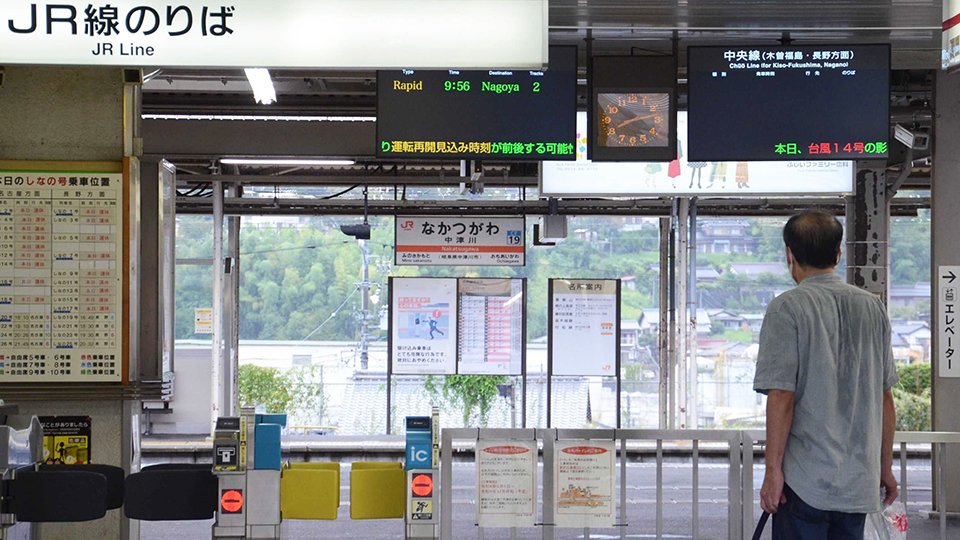 台風１４号の影響で、中央線が始発から運転見合わせとなり、電光掲示板を見つめる利用客＝２０日午前８時１３分、中津川市太田町、ＪＲ中津川駅