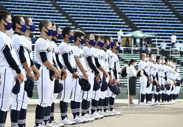 第１０３回全国高校野球選手権岐阜大会の開始式で、マスク姿で大会歌を聴く各務原西ナイン＝１０日午前９時４分、岐阜市長良福光、長良川球場