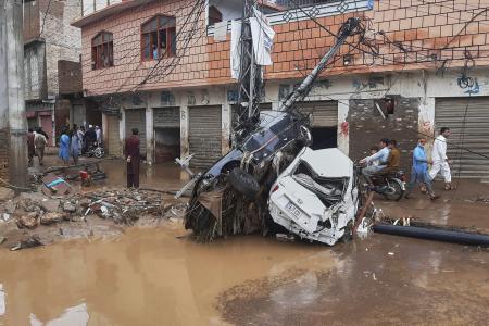 　豪雨による洪水で流され、電柱に衝突した車＝１５日、パキスタン北西部ミンゴラ近郊（ＡＰ＝共同）