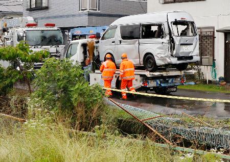 　トラックと衝突して用水路（手前）に落ちた病院の送迎車＝３日午後、埼玉県越谷市