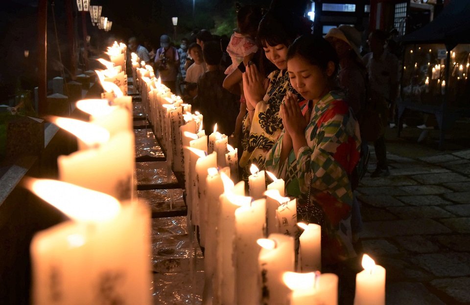 願い事の書かれたろうそくに手を合わせる参拝者ら＝１８日午後７時１０分、岐阜市粟野、大龍寺