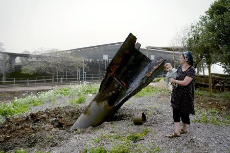 　ヨルダン川西岸のユダヤ人入植地で、イランから発射され着弾した弾道ミサイルを見るイスラエル人女性＝４月（ゲッティ＝共同）