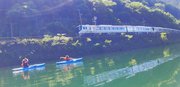 下原ダム湖にカヤックを浮かべて「ＨＣ８５系」を歓迎する住民ら＝１日午前、下呂市和佐
