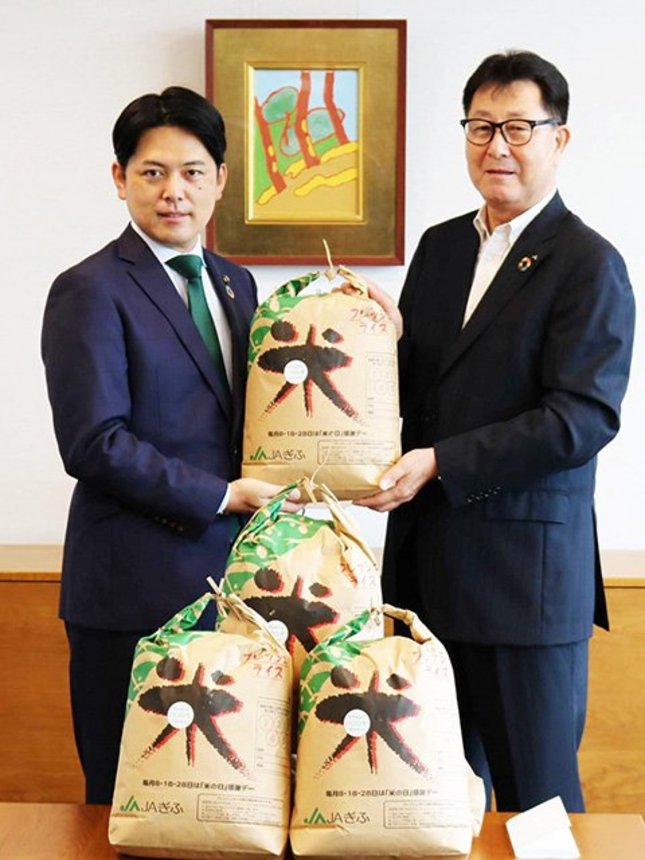 柴橋正直市長に米を手渡す櫻井宏代表理事会長（右）＝岐阜市役所
