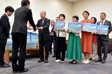 　政府側（手前）に署名を渡す議連メンバーら＝１８日午後、国会内