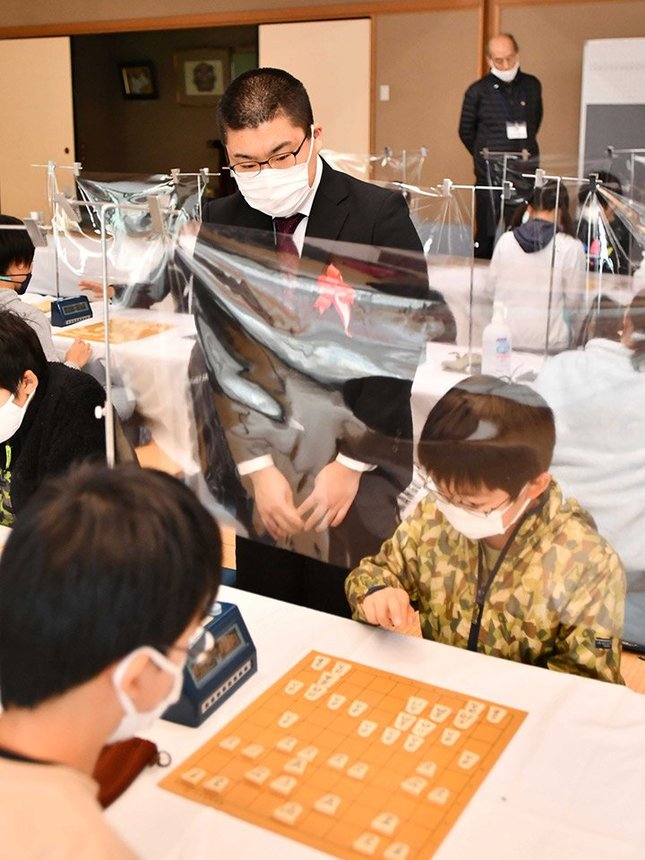 「こども将棋岐王戦」で対局を見守る高田四段＝２０２１年１２月、岐阜市金町、市文化センター