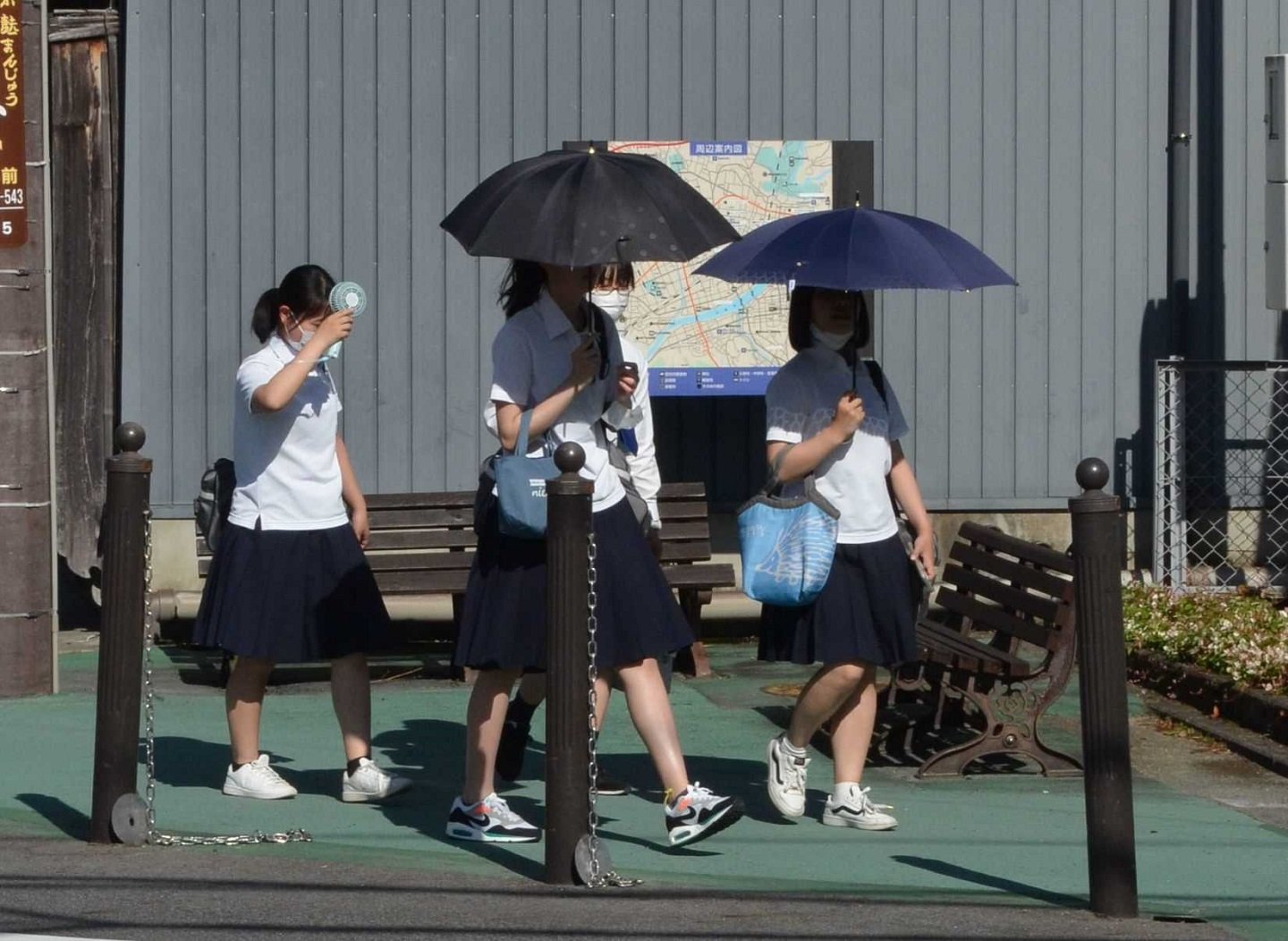 日傘や手持ち扇風機で暑さをしのぎながら下校する生徒ら＝２８日午後３時５８分、多治見市本町