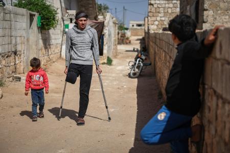 　友人とオリーブを収穫中、地雷の爆発で脚を失った男性（中央）＝４月９日、シリア北西部イドリブ県（ＡＰ＝共同）