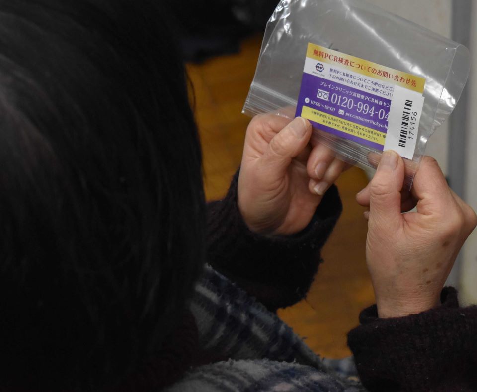 薬局でもらった無料ＰＣＲ検査の問い合わせカードを見る７０代女性
