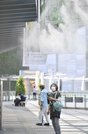 今年初の猛暑日となり、ミストシャワーの下で涼を取る女性＝４日午後１時４３分、岐阜市橋本町、ＪＲ岐阜駅前