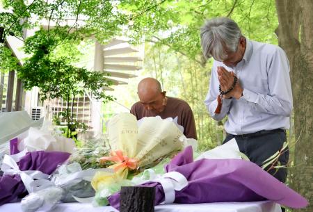 　空自機墜落事故から１年となり、献花台の前で手を合わせる人たち＝１４日午後、愛知県犬山市