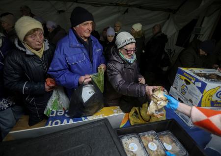 　７日、ウクライナ・キーウで、政府が運営する住民支援テントで食事を受け取る人たち（ロイター＝共同）