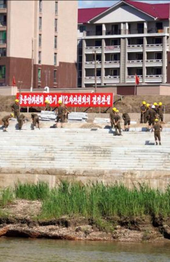　北朝鮮北西部の新義州周辺で川沿いの堤防を増築する労働者ら＝６日、中国遼寧省丹東から撮影（共同）