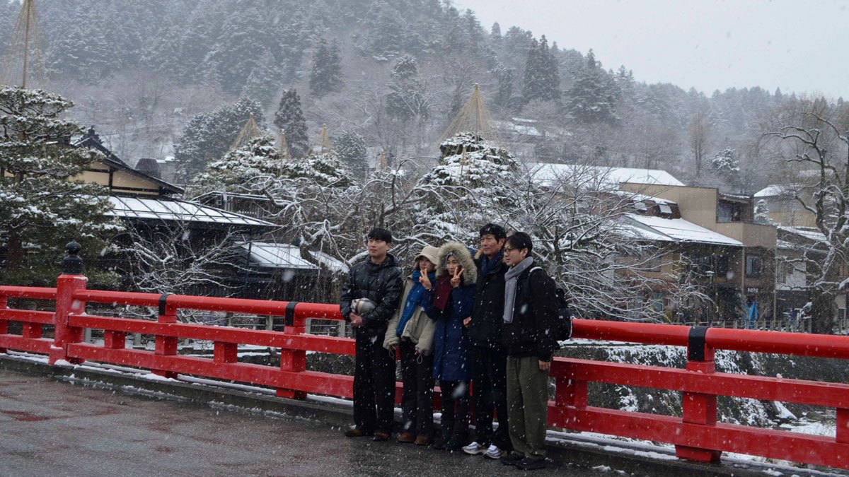 宮川の雪景色をバックに記念写真に納まる観光客＝高山市川原町、中橋