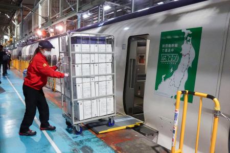 　荷物専用新幹線から積み荷を降ろす作業員＝２３日午後、東京都北区の車両基地