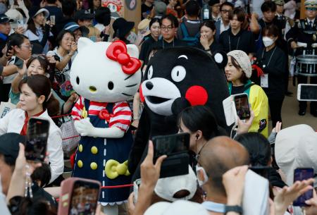 　日本のナショナルデーで、大屋根リングの下をパレードするハローキティとくまモン＝３日午後、大阪市此花区の夢洲