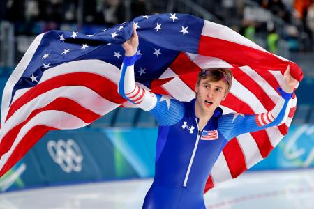 　男子５００メートルを五輪新で制し、場内を回るジョーダン・ストルツ。１０００メートルに続く２冠を達成した＝ミラノ（共同）